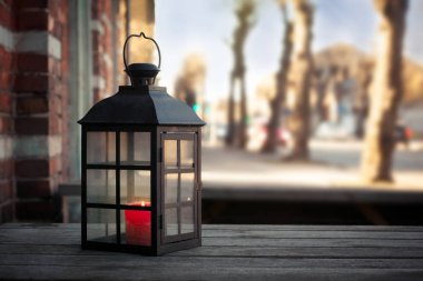 Içinde yanan mum ile Büyük metal fener, ahşap bir masada açık