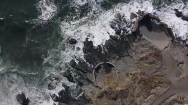 Dalgaların kayalara çarptığı deniz ve deniz kenarındaki yol.