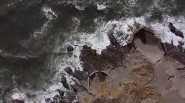 Dalgaların kayalara çarptığı deniz ve deniz kenarındaki yol.