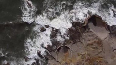 Dalgaların kayalara çarptığı deniz ve deniz kenarındaki yol.