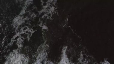 Dalgaların kayalara çarptığı deniz ve deniz kenarındaki yol.