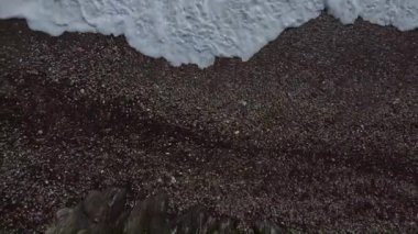 Dalgaların kayalara çarptığı deniz ve deniz kenarındaki yol.