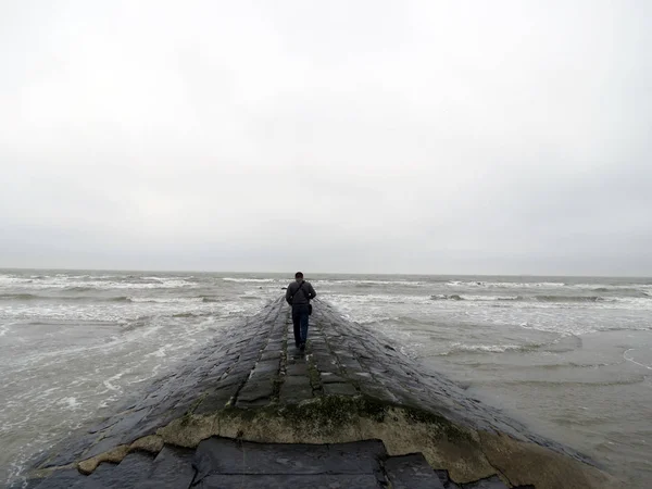 Avrupa, Belçika, West Flanders, yalnız figür üzerindesin Kuzey Denizi kıyısında bir dalgakıran