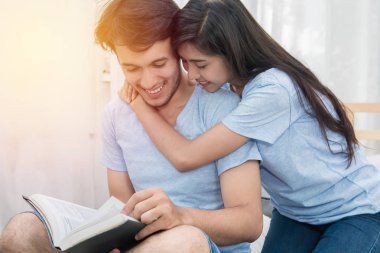 Genç seven çift yatak odalı evde üzerine bir kitap okuma.