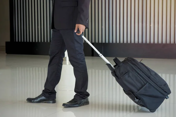 Businessman drag luggage or suitcase walking to the hotel lobby.