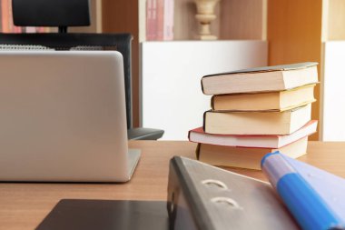 Kitap yığını ve ofiste tabloda üstünde laptop.