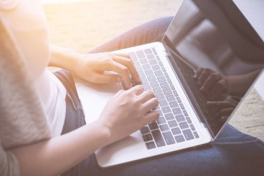 Dizüstü bilgisayarda çalışan genç bir kadın evdeki kanepede oturuyor..