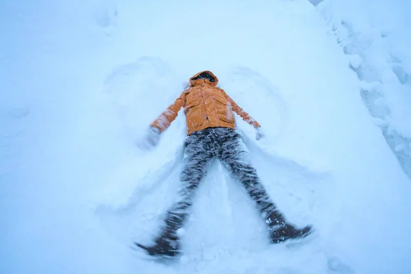 happy man lying down on the snow in winter.