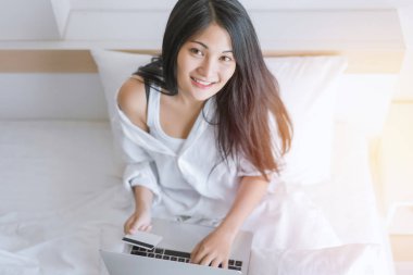 Dizüstü bilgisayarda çalışan ve kredi kartı kullanan genç bir kadın. 