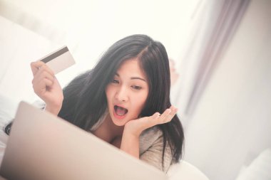 Dizüstü bilgisayarda çalışan ve kredi kartı kullanan genç bir kadın. 