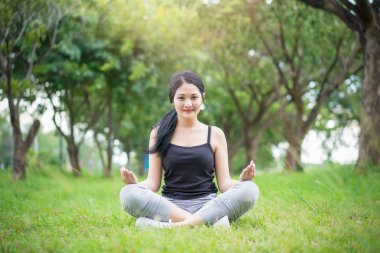 Genç bayan parkta egzersiz yapmadan önce ısınıyor.