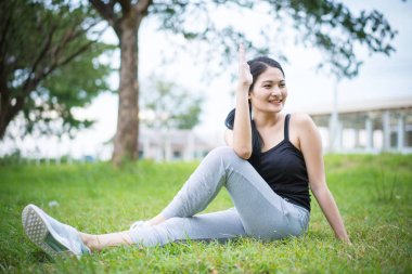 Genç bayan parkta egzersiz yapmadan önce ısınıyor.