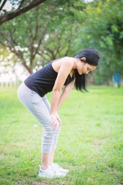 Genç bayan parkta egzersiz yapmadan önce ısınıyor.