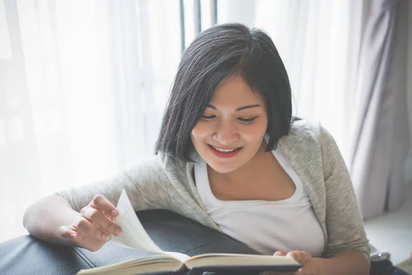 Молодая женщина читает книгу на кровати дома — стоковое фото