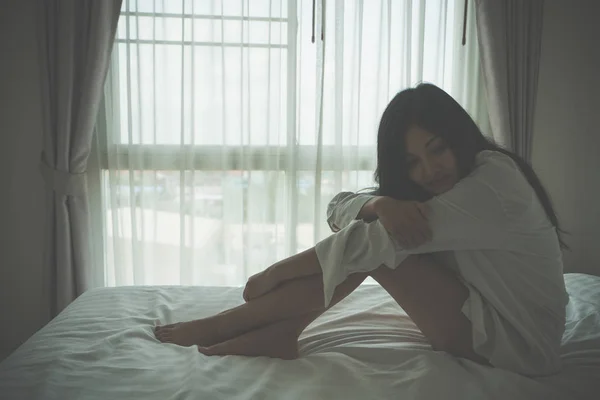 Жінка відчуває сумний пригнічений і сидить у своєму ліжку — стокове фото