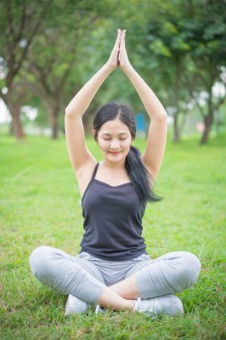 Genç bayan parkta egzersiz yapmadan önce ısınıyor.