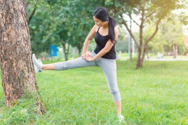Genç bayan parkta egzersiz yapmadan önce ısınıyor.