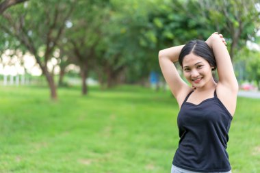 Genç bayan parkta egzersiz yapmadan önce ısınıyor.