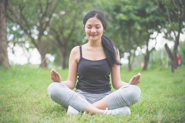 Genç bayan parkta egzersiz yapmadan önce ısınıyor.