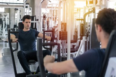 Yakışıklı adam fitness makinesinin ağırlığını düşürücü ve egzersiz 