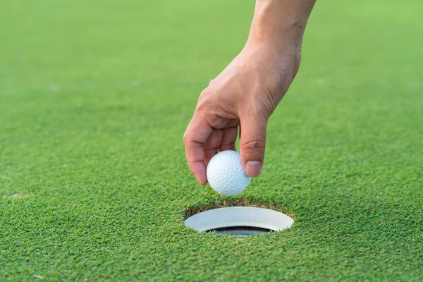 Mão pegar uma bola de golfe do fairway no campo de golfe — Fotografia de Stock