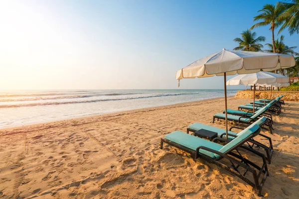 Parasole i krzesła na tropikalnej plaży z zachodem słońca — Zdjęcie stockowe