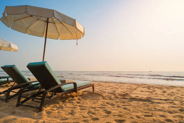 Guarda-sóis e cadeiras na praia tropical com pôr do sol — Fotografia de Stock