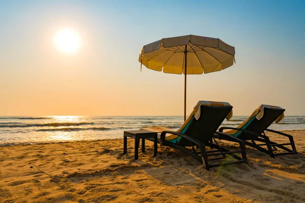 Guarda-sóis e cadeiras na praia tropical com pôr do sol — Fotografia de Stock