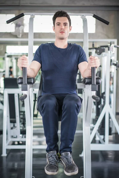 Hombre guapo ejercitando el brazo en los músculos de la máquina constructora en fitnes —  Fotos de Stock