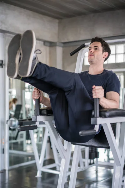 Handsome man exercising arm on machine builder muscles in fitnes