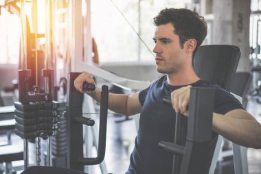 Yakışıklı adam fitness makinesinin ağırlığını düşürücü ve egzersiz 