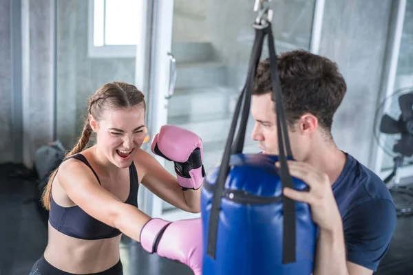 Handsome man beautiful sportswoman in boxing gloves punching bag