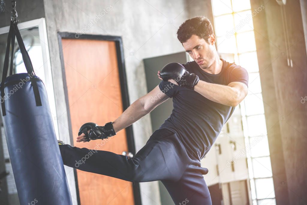 Handsome man in boxing gloves punching bags exercise in fitness 