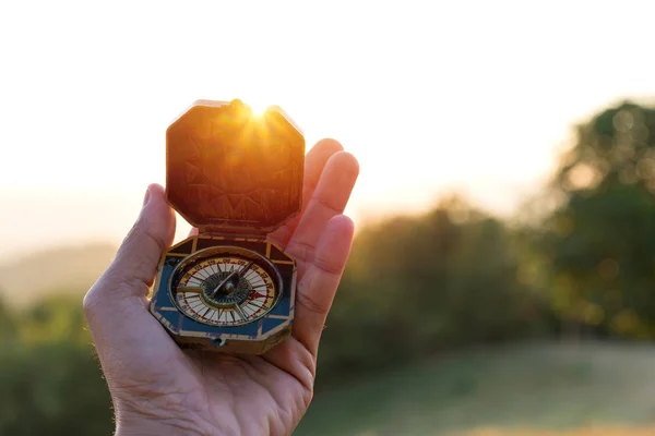 Kompass i människans hand med solnedgång natur bakgrund. — Stockfoto