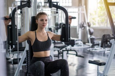 Genç kadın fitness makinesinin ağırlığını düşürücü ve i çalışma