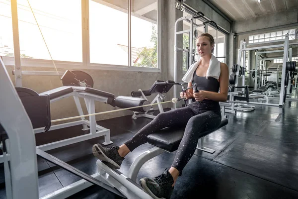 Jovem mulher abaixando o peso da máquina de fitness e trabalhando para fora i — Fotografia de Stock