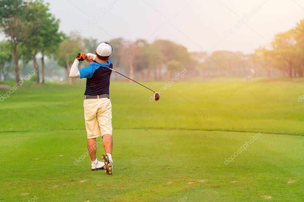 Man Golfer Hitting Ball with Club on Beatuiful Golf Course.