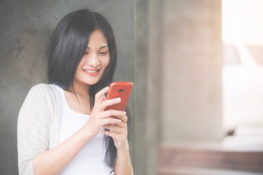 Güzel bir kadın akıllı telefon kullanıyor e-postaları kontrol ediyor, arıyor, 5G internet kullanıyor, gri arka planda duruyor, sevgilisiyle, arkadaşlarıyla sohbet ediyor. Güzel konseptin portresi