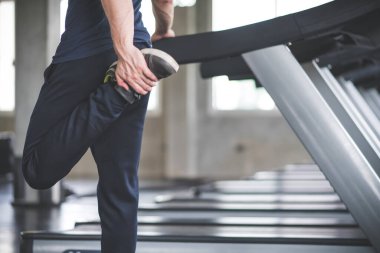 Yakışıklı adam spor salonunda spor salonunda koşu bandında koştuğu için spor salonunda egzersiz yapmadan önce ısınıyor..