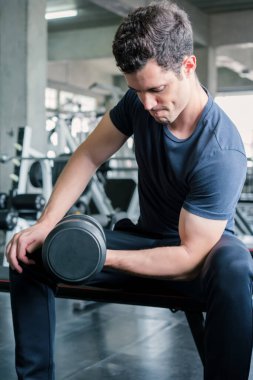 Ağırlık kaldıran yakışıklı halterci spor salonunda halterle çalışıyor.