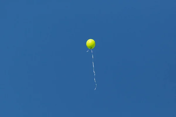 Isolated yellow balloon flying in blue sky — Stock Photo, Image