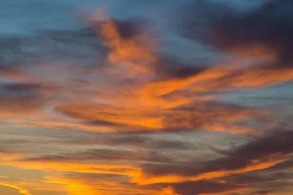 Coucher de soleil dans un ciel bleu dramatique avec des nuages dans des tons de couleur orange — Photo