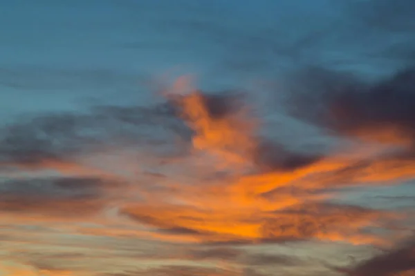 Coucher de soleil dans un ciel bleu dramatique avec des nuages dans des tons de couleur orange — Photo