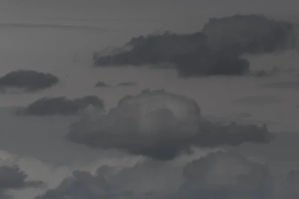 several isolated dark clouds in gray sky