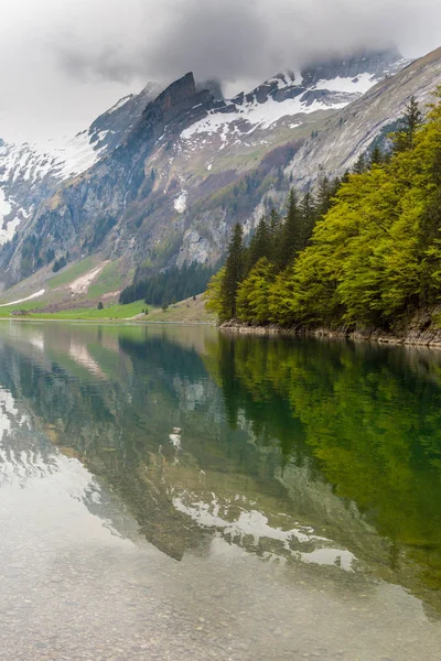 Meer Seealpsee, gereflecteerd besneeuwde bergtoppen, wolken — Stockfoto