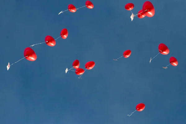 Diversi palloncini rossi a forma di cuore in volo, cielo blu — Foto Stock