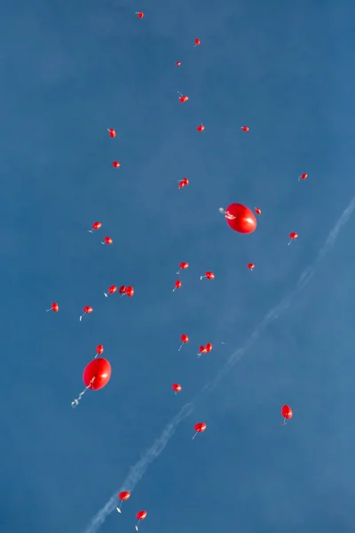 Skupina srdečních červených balónů plujících v modrém nebi — Stock fotografie