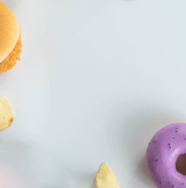 Çörek, patates cipsi gibi abur cuburlar, hamburgerler beyaz arka planda yumuşak odaklı, fotokopi alanının üst görüntüsünde.