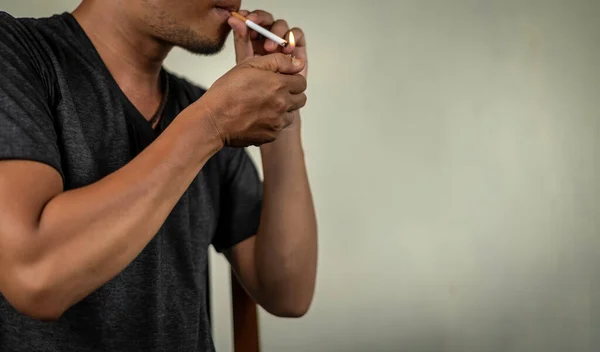 asian guy lighting a cigarette behind the wall. concept for narcotic, illness.