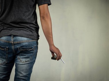 Adam duvarın arkasında yanan bir sigara tutuyor. Uyuşturucu, hastalık ve suç kavramı.